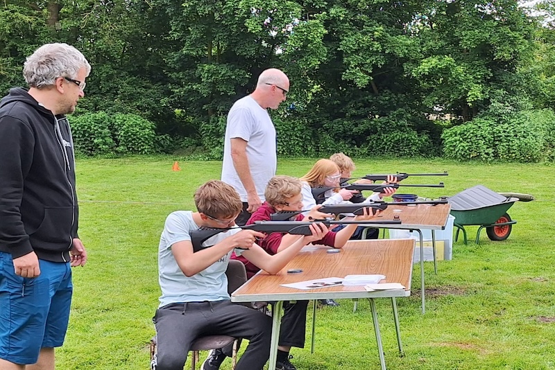 Leaders overseeing Scouts shooting air rifles